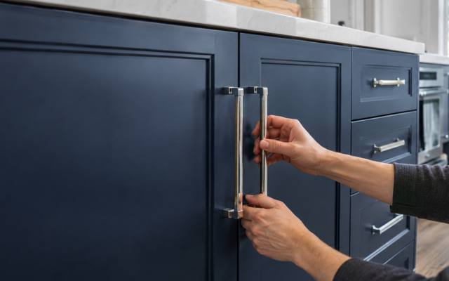 Chrome handle being attached to a navy painted door.